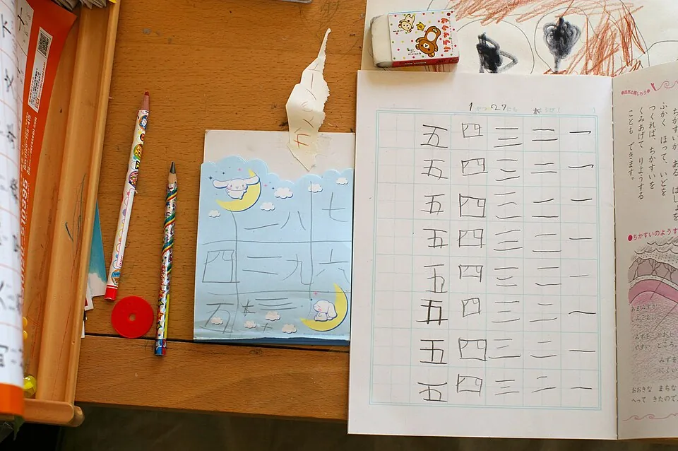 机に置かれた漢字の書き取り練習の紙と、鉛筆・消しゴム