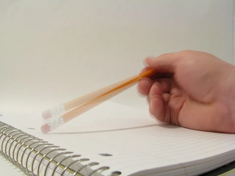 らせんとじのノートの上で鉛筆を持つ手